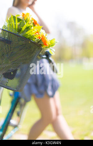 Mädchen in einem Kleid steht neben einem Fahrrad, auf einen Blumenstrauß Fokus Stockfoto