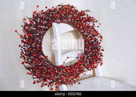 Red berry Christmas wreath hnging auf der Rückseite eines alten Stuhl. Stockfoto