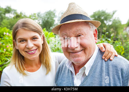 Lächelnd älterer Mann mit schönen jungen Enkelin im Park posing Stockfoto