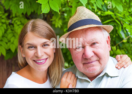 Lächelnd älterer Mann mit schönen jungen Enkelin im Park posing Stockfoto