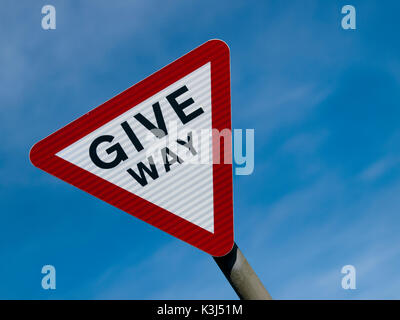 Geben weg Schild vor einem blauen Himmel Stockfoto