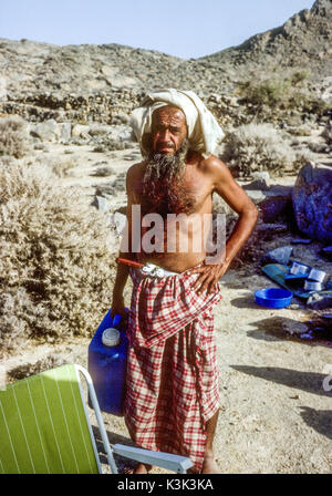 Ein einsamer Shihuh Dorfbewohner aus kargen, felsigen Buschland auf der Musandam Halbinsel, Oman, ein Top-up auf Anfrage für seine Jerry kann. Diese wenig bekannte Berg Wohnung dorfbewohner vor dem Golf arabischen Bevölkerung des östlichen Arabien und einer archaischen Sprache sprechen. Stockfoto