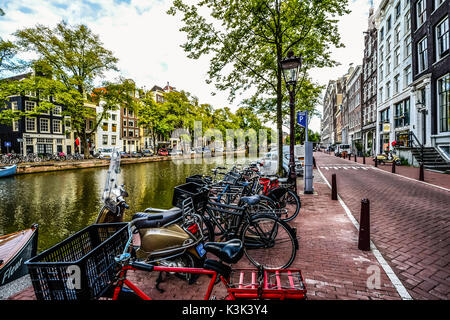 Eine typische Zeile der abgestellte Fahrräder und Motorroller an einem bewölkten Tag im frühen Herbst in Amsterdam Stockfoto