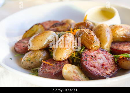 Scheiben von Jesu de Morteau auf einem Bett von Salat mit cancoillote Käse serviert, lokale Spezialität von Doubs aus der Region Bourgogne-Franche-Comté Frankreich Stockfoto