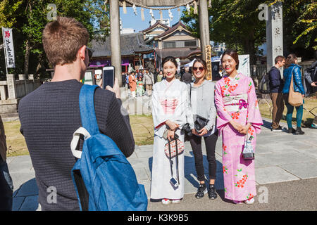 Japan, Hoshu, Tokyo, Asakusa, Asakusa Kannon Tempel aka Sensoji, Touristen Posieren mit Mädchen im Kimono Stockfoto