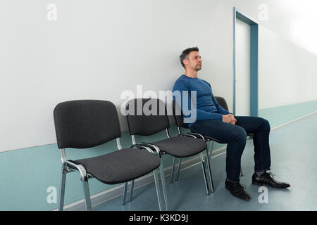 Porträt eines erwachsenen Mannes Sitzen auf Stuhl im Krankenhaus Stockfoto