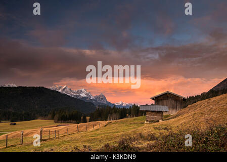 Zwei Hütten, oder Waagen vor beeindruckender Morgenstimmung mit Zugspitze im Hintergrund. Stockfoto