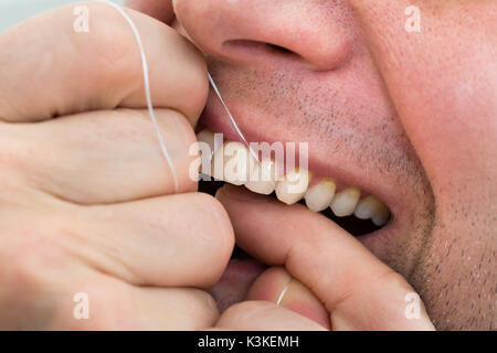 Nahaufnahme eines Mannes Flossing seine Zähne Stockfoto