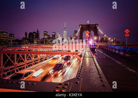 Der Verkehr auf der Brooklyn Bridge, regnerischen Abend, Wolkenkratzer und Skyline von Manhatten, New York, USA Stockfoto