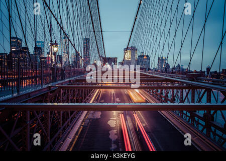 Der Verkehr auf der Brooklyn Bridge, regnerischen Abend, Wolkenkratzer und Skyline von Manhatten, New York, USA Stockfoto