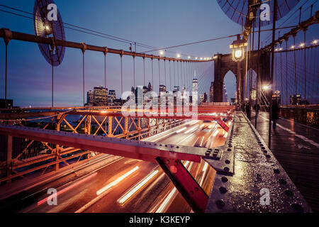 Der Verkehr auf der Brooklyn Bridge, regnerischen Abend, Wolkenkratzer und Skyline von Manhatten, New York, USA Stockfoto