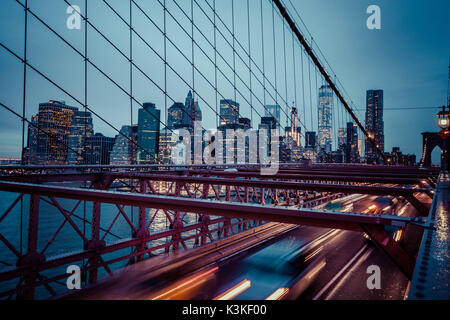 Der Verkehr auf der Brooklyn Bridge, regnerischen Abend, Wolkenkratzer und Skyline von Manhatten, New York, USA Stockfoto