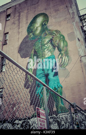 Hinterhof Szene Graffiti eines grünen Supermacht Baby, Little Italy, Manhatten, New York, USA Stockfoto