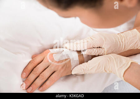Nahaufnahme der Ärztin Hand mit Infusion eingefügt in die Hand des Patienten Stockfoto