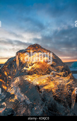 Gletscherlagune Jokulsarlon, Island. Sonnenlicht Reflexionen über ein kleines schwarzes Eis am Ufer. Stockfoto