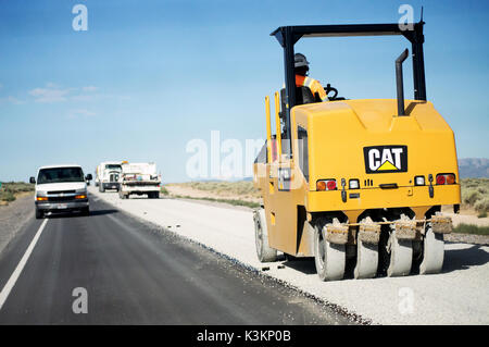 Ein Bauarbeiter einen aspahlt compactor Resurfacing eine Straße in der Wüste. Stockfoto