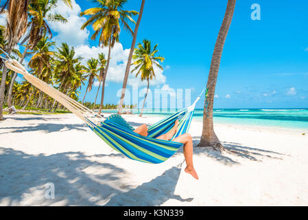 Canto de la Playa, Saona, East National Park (Parque Nacional del Este), Dominikanische Republik, Karibik. Frau entspannen auf einer Hängematte am Strand (MR).