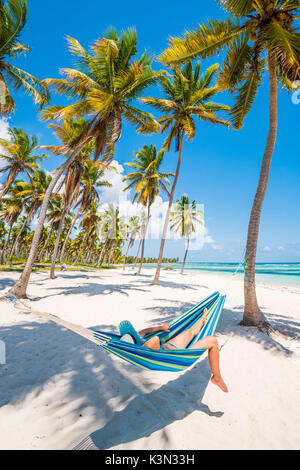 Canto de la Playa, Saona, East National Park (Parque Nacional del Este), Dominikanische Republik, Karibik. Frau entspannen auf einer Hängematte am Strand (MR). Stockfoto