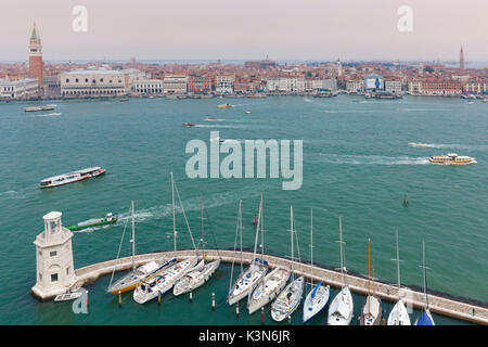 Europa, Italien, Venetien, Insel San Giorgio Maggiore. Einer der Scheinwerfer der Dock und einige angelegte Boote, im Hintergrund St. Mark und das historische Zentrum von Venedig Stockfoto