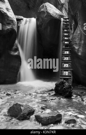 Schwarze und weiße lange Exposition am Wasserfall und Leiter in Kanarra Creek Canyon. Kanarraville, Bügeleisen County, Utah, USA. Stockfoto