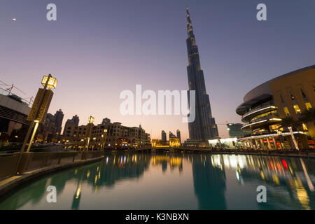 Der Burj Khalifa, Wolkenkratzer und andere Gebäude sind in den gleichnamigen See bei Sonnenuntergang leuchten wider. Dubai, Vereinigte Arabische Emirate Stockfoto