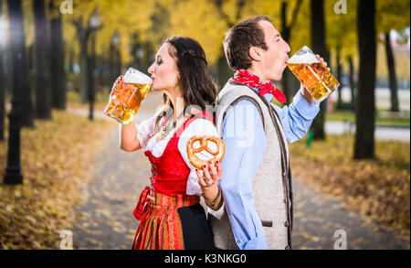 Paar tragen Tracht Rücken-an-Rücken und Bier trinken. Stockfoto