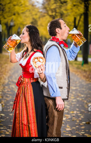 Paar tragen Tracht Rücken-an-Rücken und Bier trinken. Stockfoto