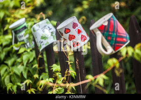 Keramikbecher, die am hölzernen Gartenzaun hängen, ein Becher mit Herzen und Stillleben Tschechien Stockfoto