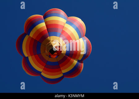 Ein Regenbogen farbige Heißluftballon direkt schwimmt oben in der blauen Morgenhimmel. Stockfoto