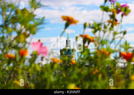 Turm mit Uhr und eine goldene Statue von Schloss Charlottenburg in Berlin durch unscharfe Blumen im Garten gesehen Stockfoto