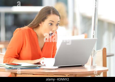 Single erstaunt Student finden erstaunliche Inhalten in einem Laptop in einem Restaurant sitzen Stockfoto