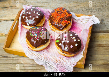 Dekoriert Donuts, serviert auf einem Tablett aus Holz Stockfoto