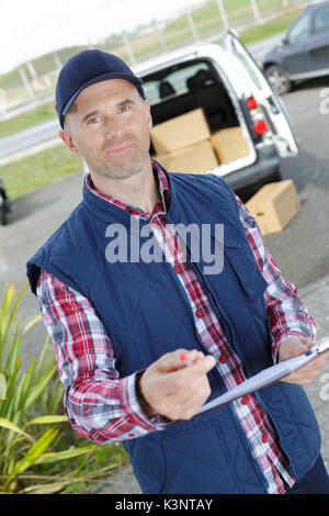 Delivery man Schreiben auf Zwischenablage vor seinem Van Stockfoto