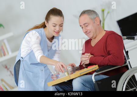 Care Worker, die einen älteren Mann sein Abendessen Stockfoto