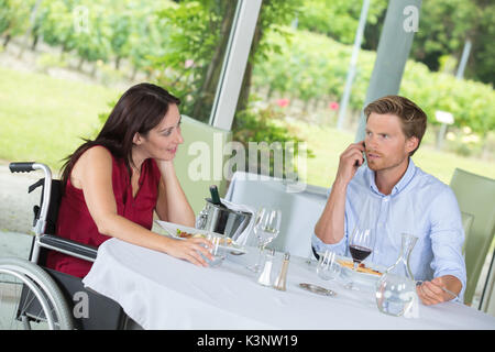 Frau gelangweilt auf dem neuesten Stand, während ihr Freund in Business Call Stockfoto