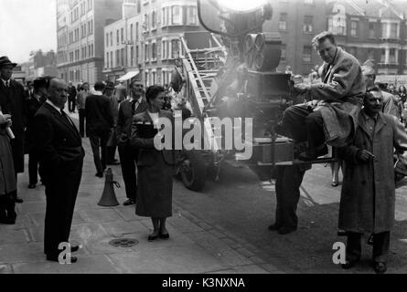 Der Mann, der zuviel wusste [USA 1956] [L - R] James Stewart [Hintergrund extreme] Regisseur Alfred Hitchcock links, Technischer Berater/Script Supervisor BODENSEE WILLIS [center], und nicht identifizierte Kamera crew Datum: 1956 Stockfoto