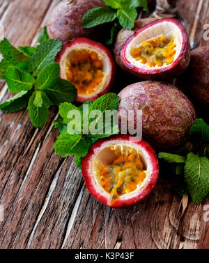 Juicy Fruit Granadilla mit Minze auf einem Holztisch mit einem Cocktail, selektiver Fokus Stockfoto