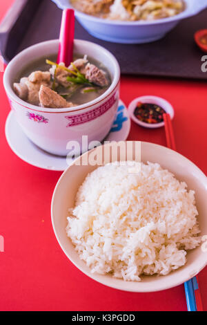 Schweinerippchen Suppe mit Jasmin Reis auf rotem Hintergrund, Efeu Kürbis Suppe mit Schweinerippchen Stockfoto