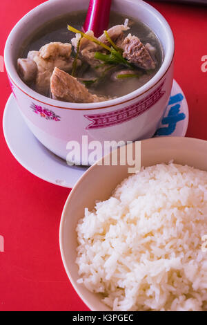 Schweinerippchen Suppe mit Jasmin Reis auf rotem Hintergrund, Efeu Kürbis Suppe mit Schweinerippchen Stockfoto