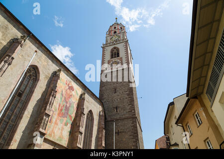 Die mittelalterliche Kirche des Hl. Nikolaus im Zentrum von Meran in Südtirol, Italien; es ist ein farbenfrohes Fresko von St Christopher auf der Außenseite. Stockfoto