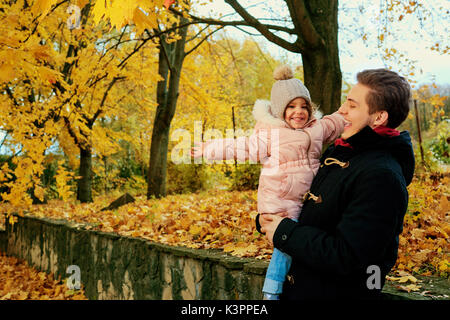 Ein Vater geht mit einem Kind Tochter im Park im Herbst. Stockfoto