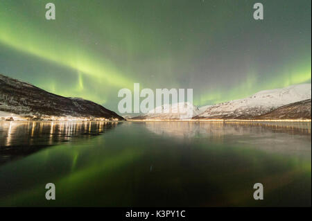 Die Northern Lights ist in der eisigen Meer von schneebedeckten Gipfeln Manndalen Kafjord Lyngen Alpen Tromsø Norwegen Europa umgeben wider Stockfoto