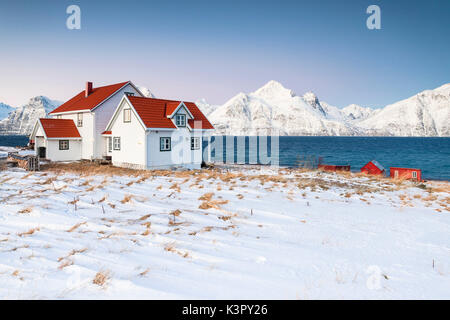 Blauer Himmel über die Holzhütten genannt Rorbu eingerahmt von gefrorenen Meer und schneebedeckten Gipfeln Djupvik Lyngen Alpen Tromsø Norwegen Europa Stockfoto