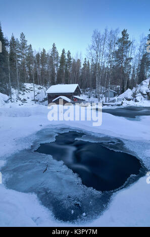 Die abenddämmerung Frames das gefrorene Wasser in den verschneiten Wäldern und der holzhütte Juuma Myllykoski Lappland Region Finnland Europa Stockfoto