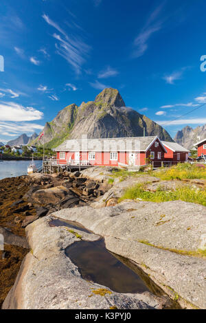 Typische Häuser der Fischer namens Rorbu von felsigen Gipfeln und blaues Meer Reine Moskenes Lofoten norwegen Europa gerahmt Stockfoto