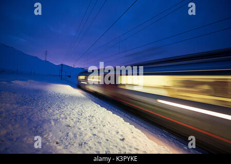 Bernina Express fährt schnell in die verschneite Landschaft in der Dämmerung Berninapass Kanton Graubünden Engadin Schweiz Europa Stockfoto