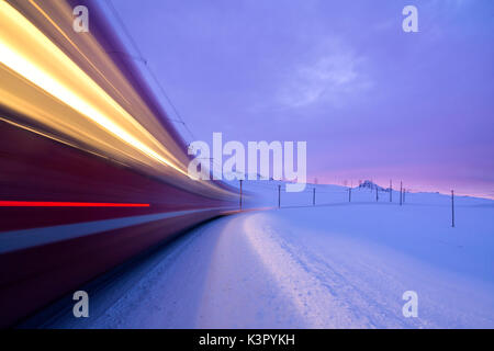 Bernina Express fährt schnell in die verschneite Landschaft in der Morgendämmerung Berninapass Kanton Graubünden Engadin Schweiz Europa Stockfoto