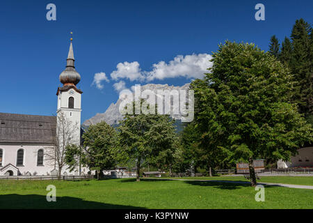 Typische Kirche alpinen Dorfes umgeben von Gipfeln und Wald Garmisch Partenkirchen Oberbayern Region Bayern Deutschland Europa Stockfoto