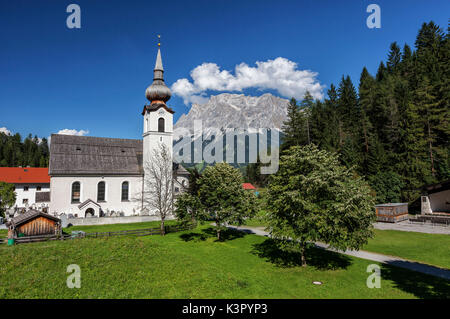 Typische Kirche alpinen Dorfes umgeben von Gipfeln und Wald Garmisch Partenkirchen Oberbayern Region Bayern Deutschland Europa Stockfoto