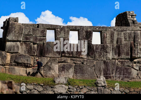 Ein Tourist zu Fuß rund um den Inka Ruinen von Machu Picchu durch den Tempel der drei Fenster, bestehend aus nur drei Wände auf einer rechteckigen Basis sowie durch ein Dach von Adobe Wände aus großen Blöcken fester Fels in polygonalen Form geschnitzt ein Konglomerat von perfekt aufeinander abgestimmte Steine jeder andere Formen konstruiert gedeckt, sodass Platz für, ursprünglich fünf Fenster, obwohl es heute nur drei von ihnen angibt, die genaue Lage der Sunrise Peru Südamerika Stockfoto